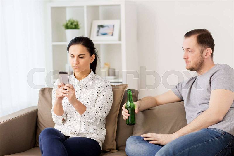 People, relationship difficulties and conflict concept - man drinking beer and woman with smartphone having argument at home, stock photo