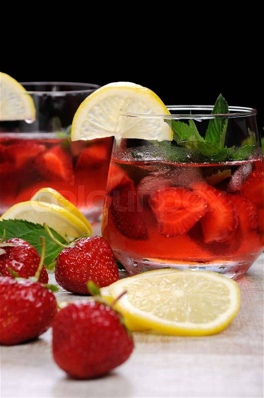 A glass of chilled strawberry lemonade, mint leaves, a slice of lemon with ice, stock photo