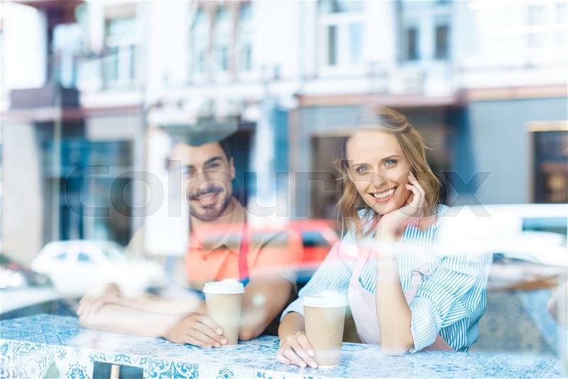 Young workers drinking coffee and smiling at camera through window , stock photo