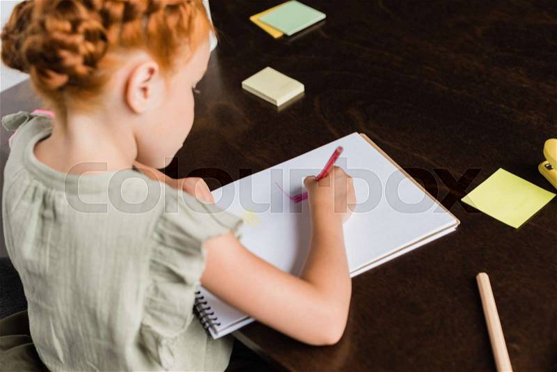 Beautiful redhead little girl drawing in album, stock photo