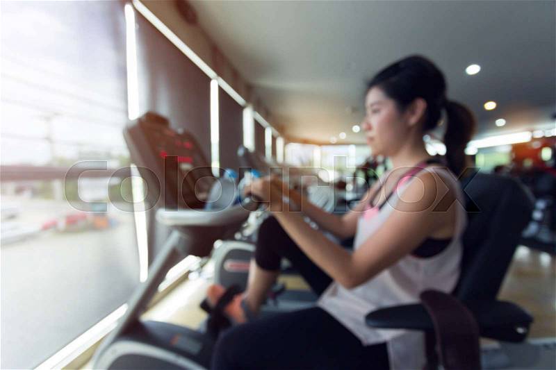 Woman cycling burn fat on bicycle cardio machine in fitness gym exercise sport club center, blurred image used for your background, stock photo