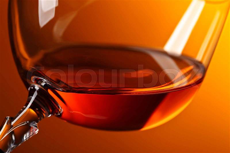 Snifter of brandy with copy space for text on a yellow background, stock photo