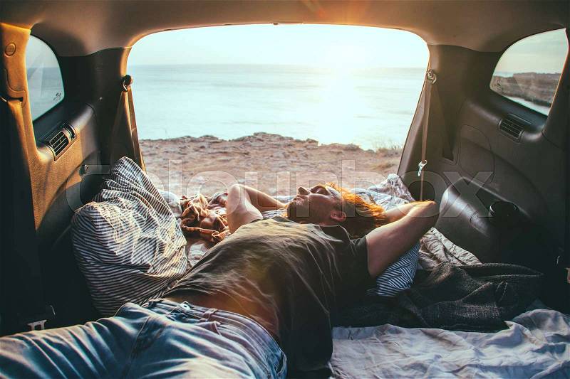 Man relaxing and sleeping inside car trunk. Fall trip in sunset. Freedom travel concept. Autumn weekend, stock photo