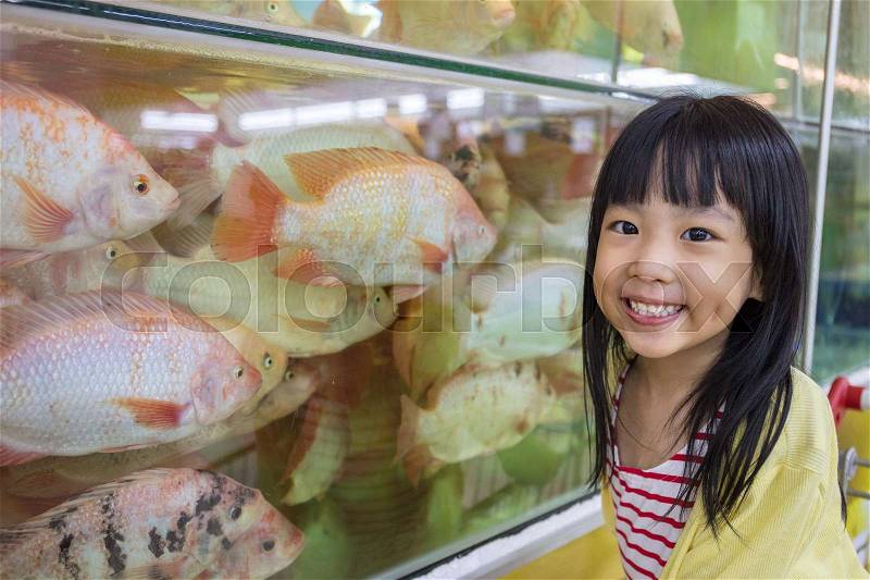 Asian Little Chinese Girl watching fish in supermarket, stock photo