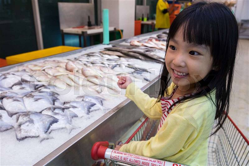 Asian Little Chinese Girl choosing seafood in supermarket, stock photo