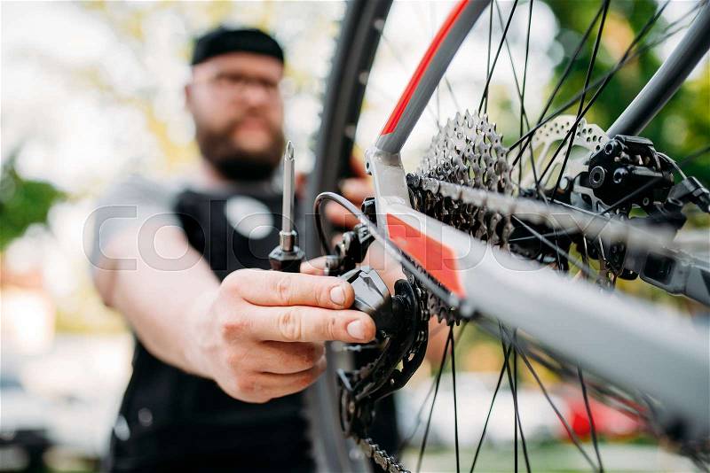 Bicycle mechanic repair bike with broken speed shifter, cycle workshop outdoor. Bicycling sport, service man work with wheel, stock photo