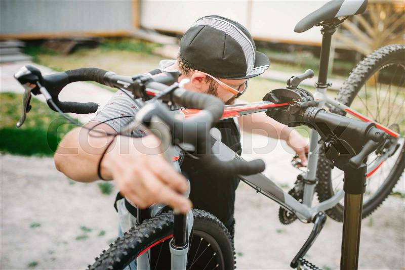 Bicycle mechanic repair bike, top view. Cycle workshop outdoor. Bicycling sport, bearded service man work with wheel, stock photo
