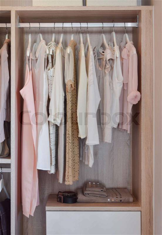 Modern closet with row of dresses hanging in wooden wardrobe, stock photo
