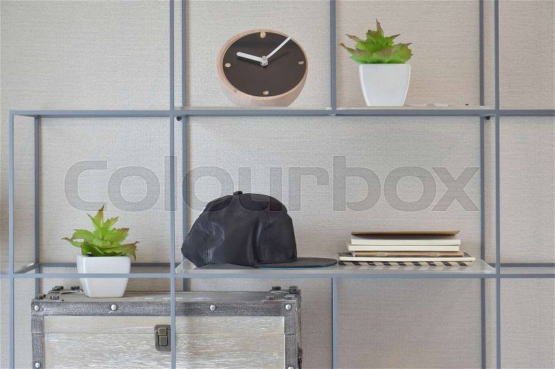 Decorative shelf on wall with books, black caps, wooden clock and vase, stock photo