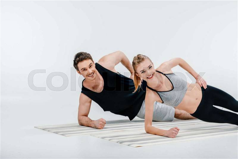 Young beautiful couple doing side plank isolated on white, stock photo