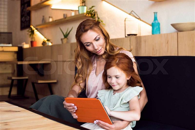 Beautiful happy mother and daughter using digital tablet together , stock photo
