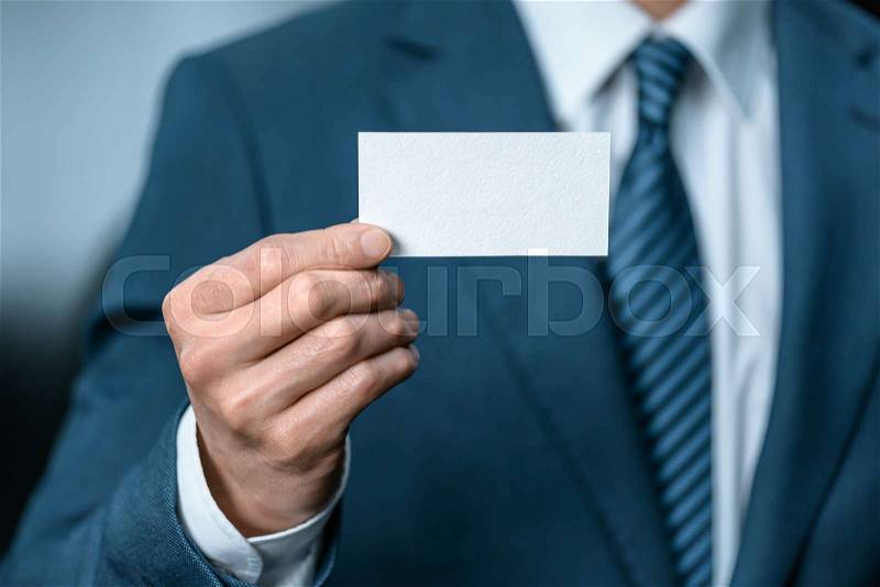 Selective focus of businessman in suit showing business card in hand, stock photo