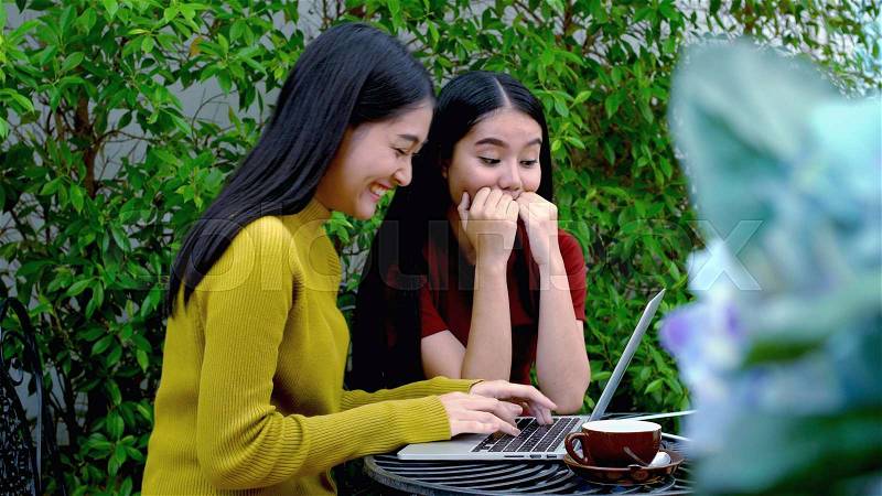 The two asian lovely girls were excited and cheerful when to get a good news on internet from laptop computer, Dolly shot with teenager lifestyle concept, stock photo