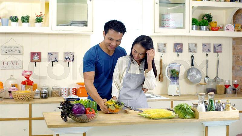 The young asian wife is preparing to make a vegetables salad for her newly awake husband and walks into the kitchen. family concept, stock photo