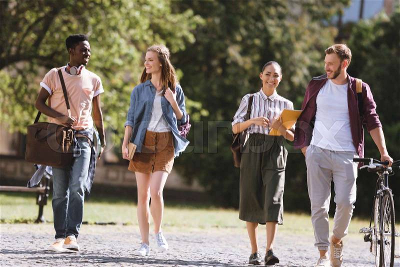 Group of happy multicultural students walking together in park, stock photo