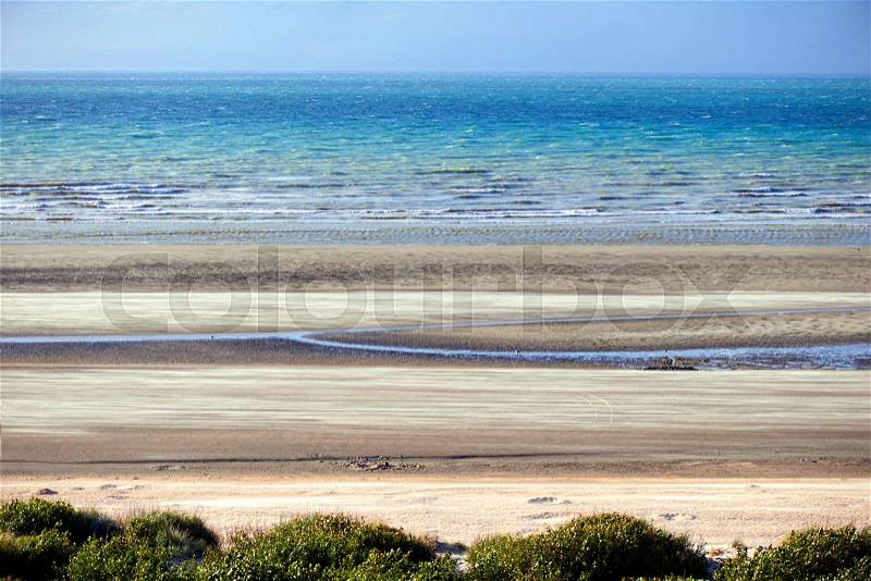 Low tide and motion flying sand at the North sea in Belgium, De Panne, stock photo
