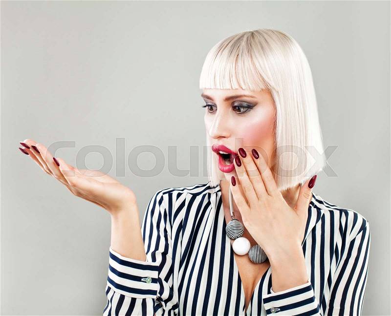Surprised Woman Showing Empty Copy Space on the Open Hand. Empty Hand, Fashion Makeup, Blonde Hair, stock photo