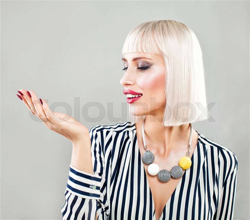 Happy Surprised Woman Showing Empty Copy Space on the Open Hand. Empty Hand, Fashion Makeup, Blonde Hair, stock photo