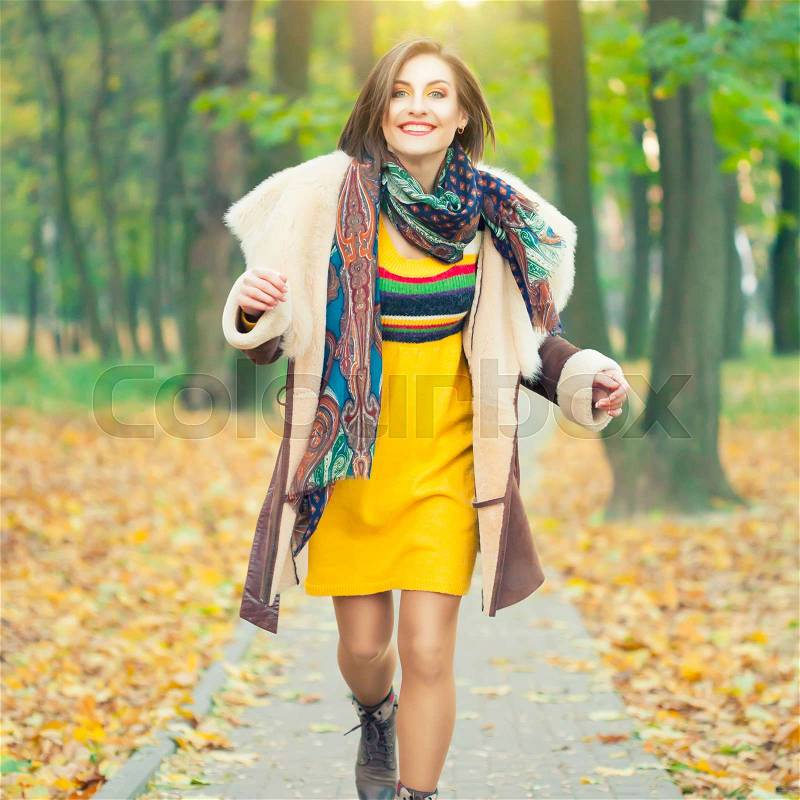 Beautiful young woman running in autumn park, stock photo