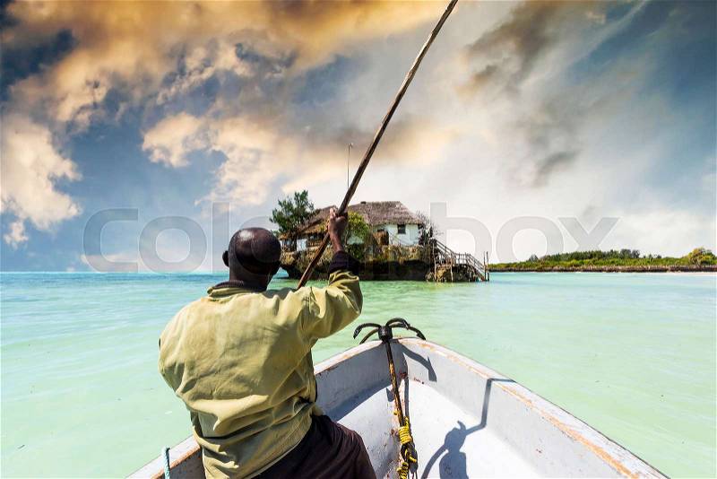 Arfican on the boat sailing to the Rock restaurant in ocean on the horizon, Zanzibar, stock photo