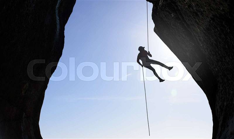 Man rock climber silhouette over bright sun background, stock photo