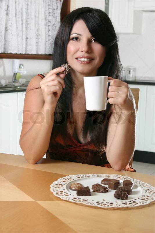 A beautiful woman enjoys coffee and chocolates, stock photo