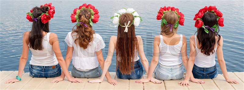 Back view of five young ladies, wearing flower wreaths, jeans and white tshirts. Group of friends sitting on the side of the pool or on pier. Pool party, summer vacation. Banner for website, stock photo