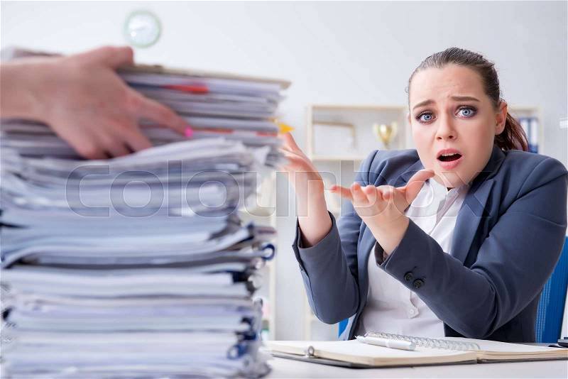 Tired businesswoman with paperwork workload, stock photo