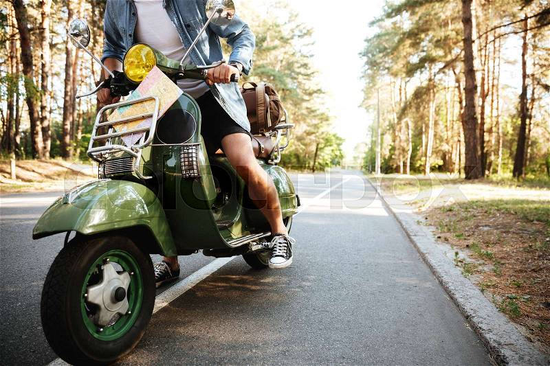 Cropped picture of young man on scooter outdoors, stock photo