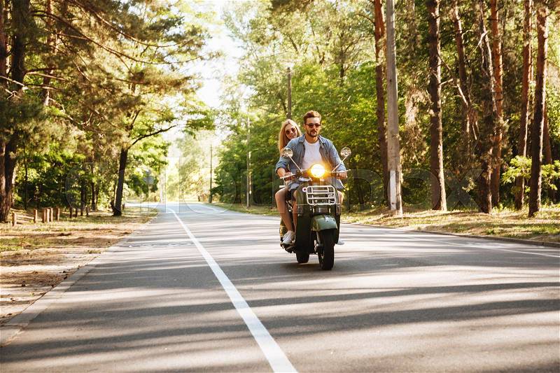 Image of serious young bearded man on scooter with girlfriend outdoors. Looking aside, stock photo