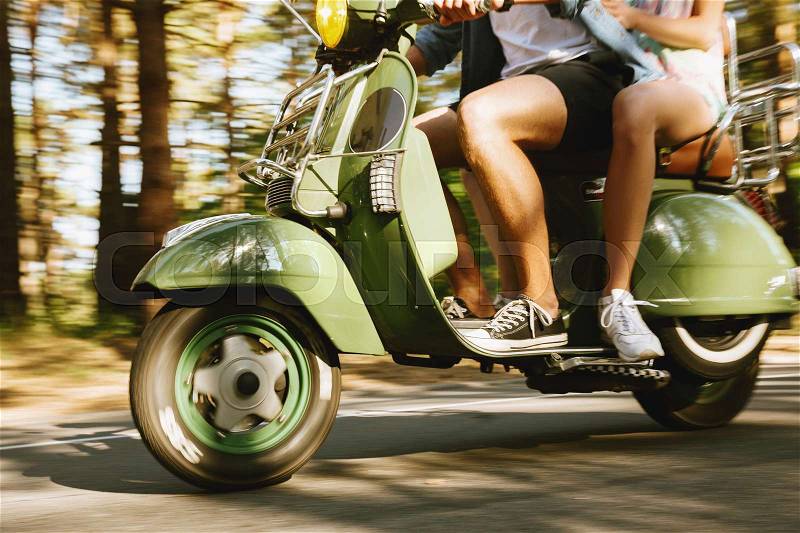 Cropped image of young bearded man on scooter with girlfriend outdoors, stock photo