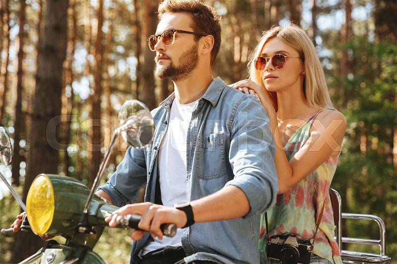 Picture of young bearded man on scooter with girlfriend outdoors. Looking aside, stock photo