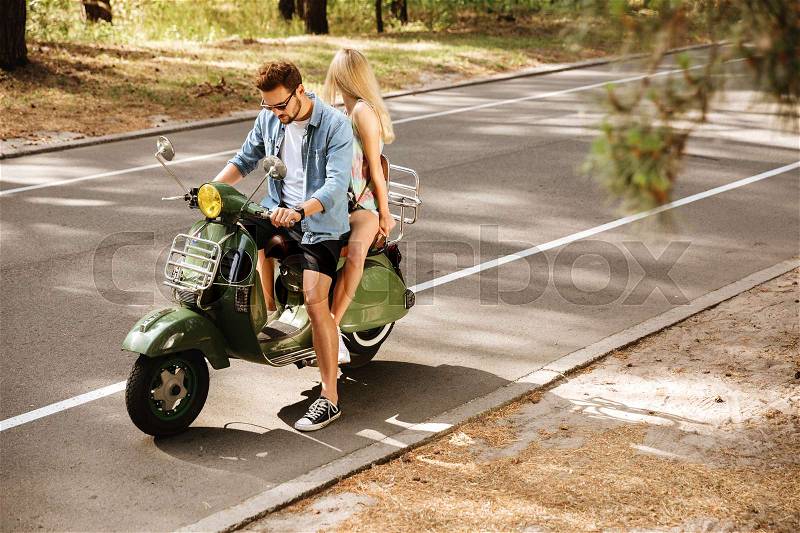 Photo of young man on scooter with girlfriend outdoors. Looking aside, stock photo