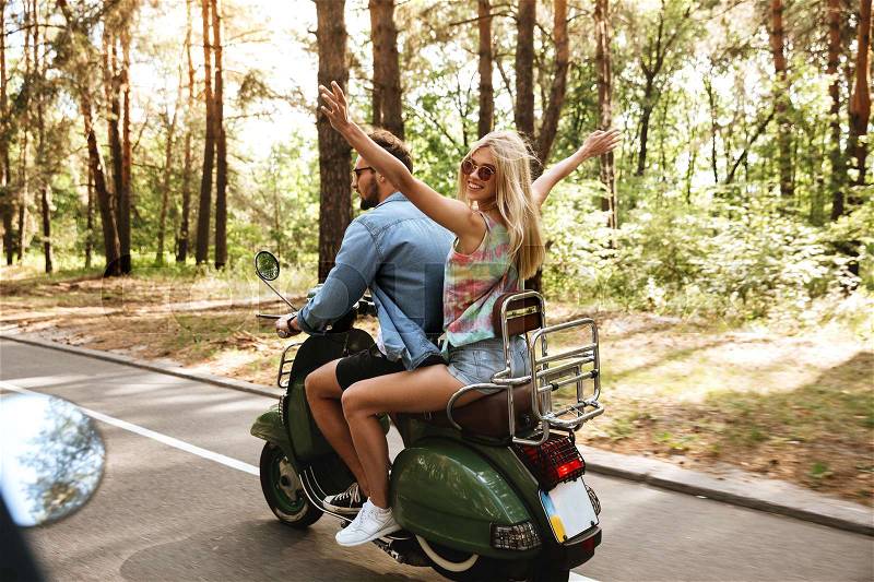 Picture of young loving couple man on scooter with girlfriend outdoors. Looking aside, stock photo