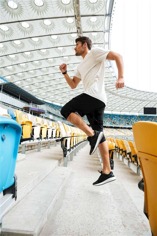 Side view of a sporty athlete man running upstairs at the stadium, stock photo