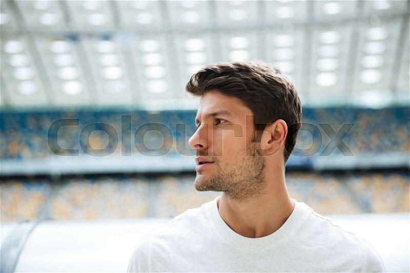 Close up portrait of a handsome sportsman looking away with stadium on a background, stock photo