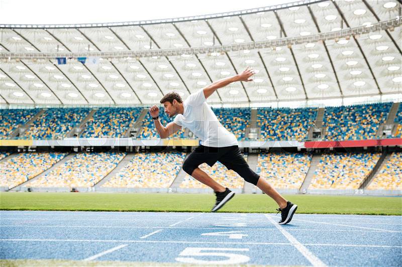 Side view of a sport man running on a racetrack at the stadium, stock photo