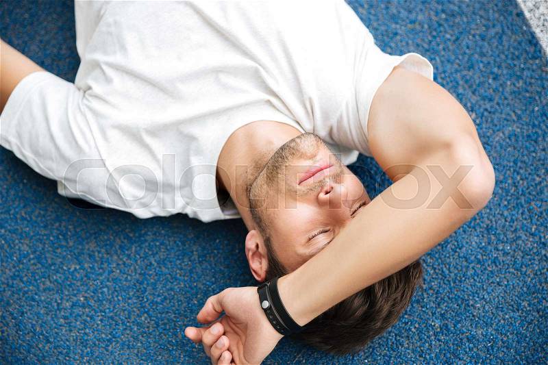 Exhausted sportsman finished his race and resting on a racetrack, stock photo