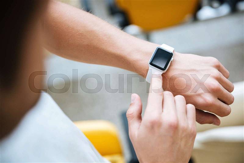 Cropped photo of young sports man looking at watch at the stadium outdoors, stock photo