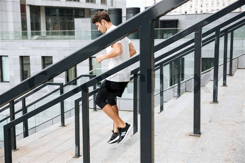 Side view of a sporty athlete man running downstairs at the stadium, stock photo