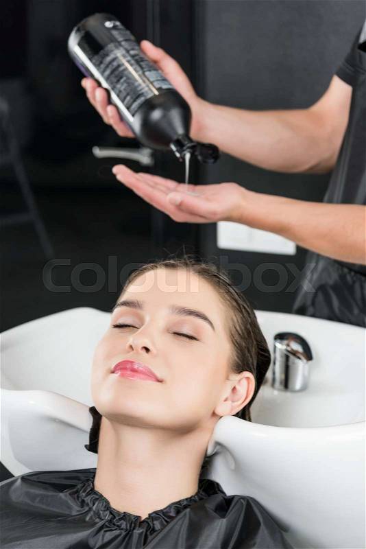 Happy smiling woman having hair wash in beauty salon, stock photo