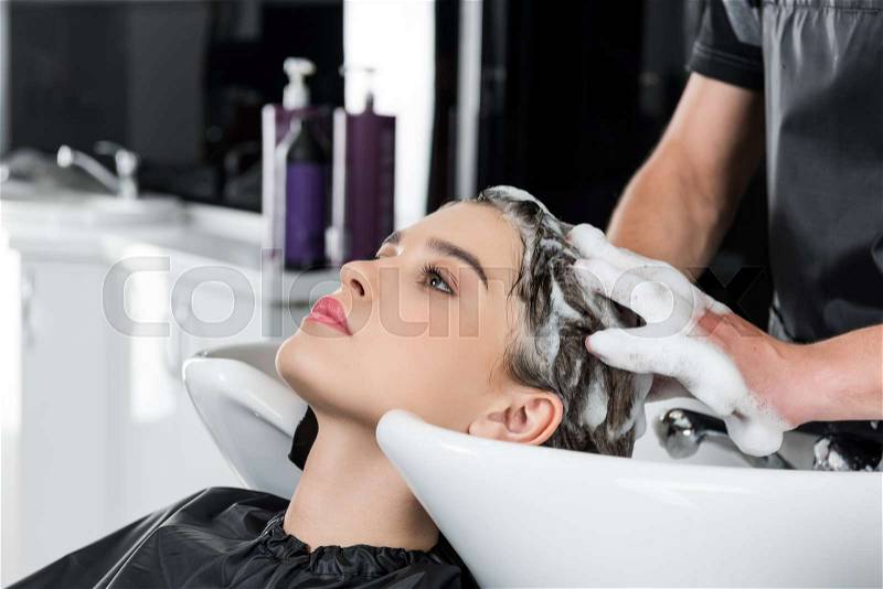 Young beautiful woman having hair wash in beauty salon, stock photo