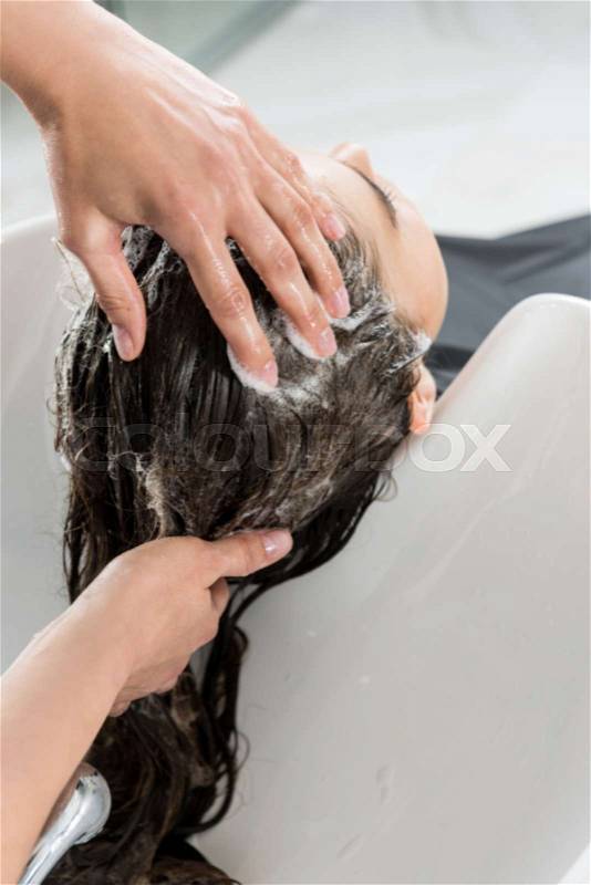 Cropped shot of woman having hair wash in beauty salon, stock photo