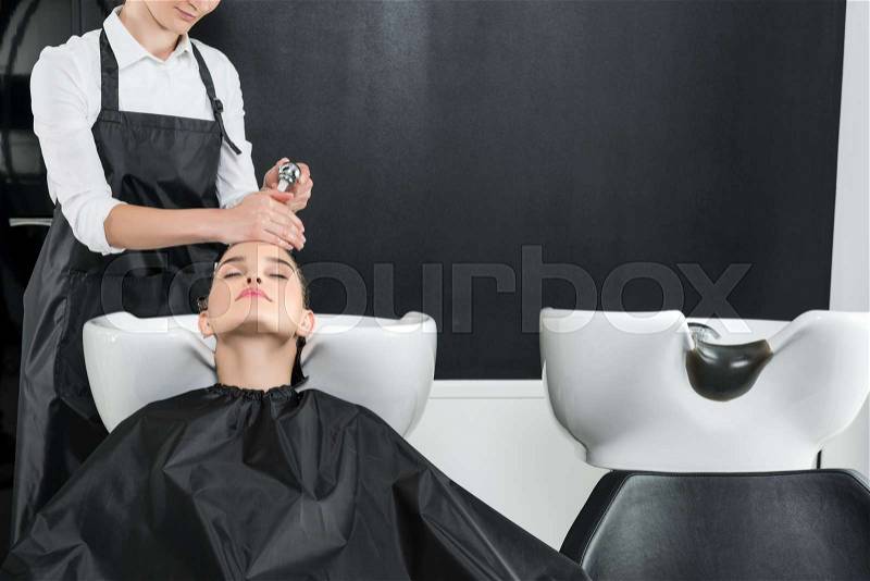 Young woman having hair wash in beauty salon, stock photo
