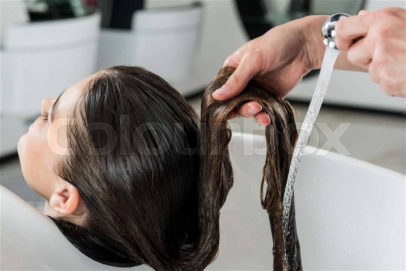 Close-up shot of woman having hair wash in beauty salon, stock photo