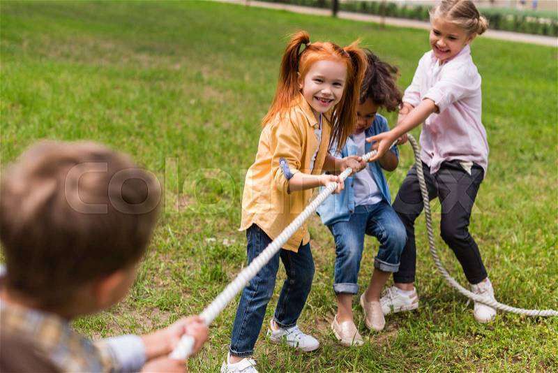 Happy beautiful multiethnic kids pulling rope in park , stock photo