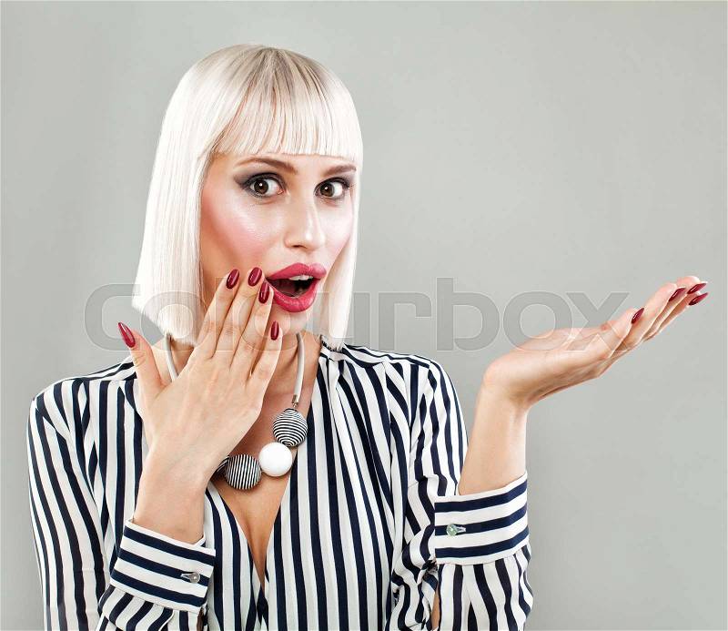 Surprised Fashion Model Woman Showing Empty Copy Space on the Open Hand. Empty Hand, Fashion Makeup, Blonde Bob Hairstyle, Fashion Cloth, stock photo