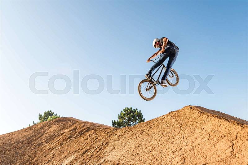 Bmx rider performing a look back at a dirt trail park, stock photo