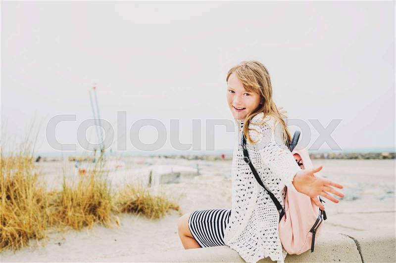 Little girl enjoying summer vacation by the sea, wearing stripe nautical dress and backpack. Image taken in Saintes-Maries-de-la-Mer, capital of Camargue, south of France, stock photo