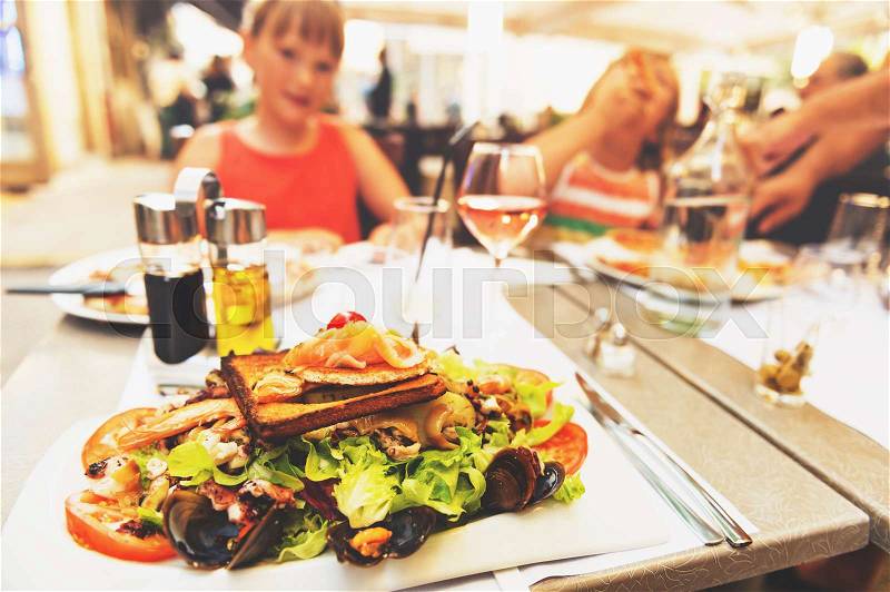 Seafood salad served in the restaurant, family dining outside during summer vacation on south of France, stock photo